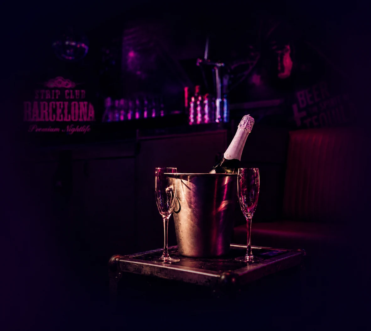 Champagne bucket and VIP drinks inside a Barcelona strip club with dark purple nightlife lighting